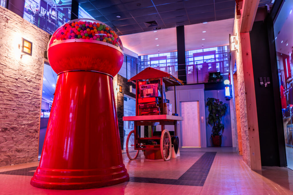 Purpose-built indoor mall scenario at Decision Tactical in North Orlando, featuring a giant red gumball machine, a vendor cart stacked with boxes, a barber pole, storefronts, and an elevator lobby set up for law enforcement scenario training.